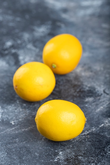 Tre succosi limoni maturi hanno posto la superficie di marmo