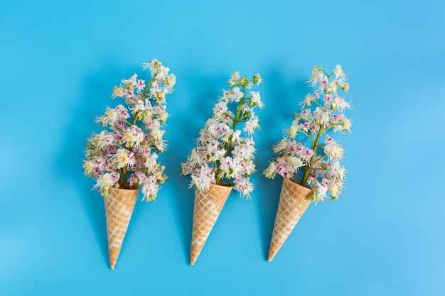 Tre tazze di cialda croccante dolce con fiori di castagno su sfondo blu