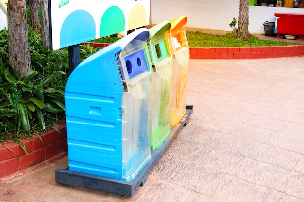 Tre tipi di bidoni della spazzatura blu verde e arancione nel parco