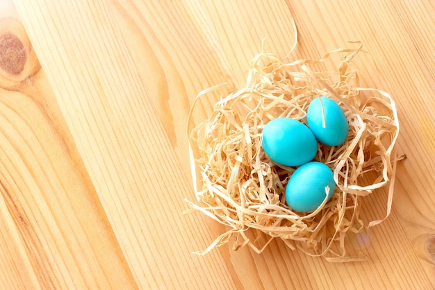 Tre uova blu in un nido su uno sfondo in legno chiaro. Pasqua celebra il concetto.