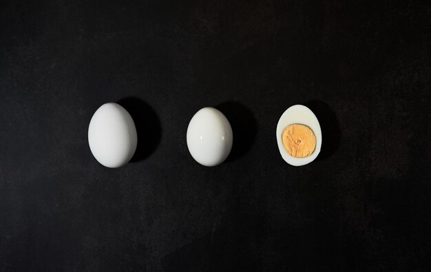 Tre uova di gallina giacciono sulla vista dall'alto del tavolo da cucina nero