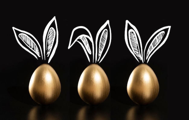 Tre uova di pasqua d'oro con orecchie disegnate su di esse, una delle quali ha orecchie di coniglio.