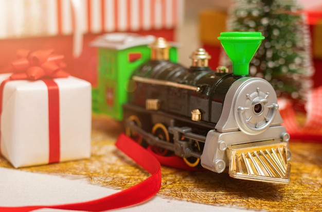 Trenino di Natale in miniatura sullo sfondo di scatole regalo Concetto di celebrazione di Natale e Capodanno Messa a fuoco selettiva