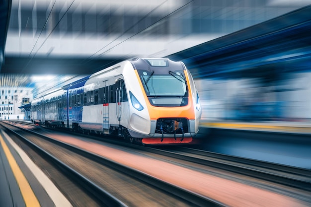 Treno ad alta velocità in movimento sulla stazione ferroviaria al tramonto Moderno treno passeggeri interurbano con effetto motion blur sulla piattaforma ferroviaria Ferrovia industriale in Europa Industria dei trasporti