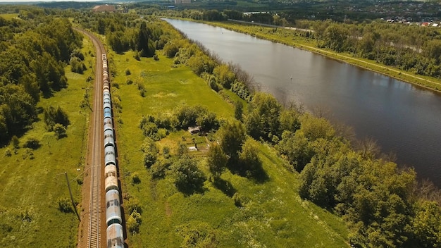 Treno merci con cisterne e contenitori sulla ferrovia ferroviaria e autostrada con veduta aerea di automobili