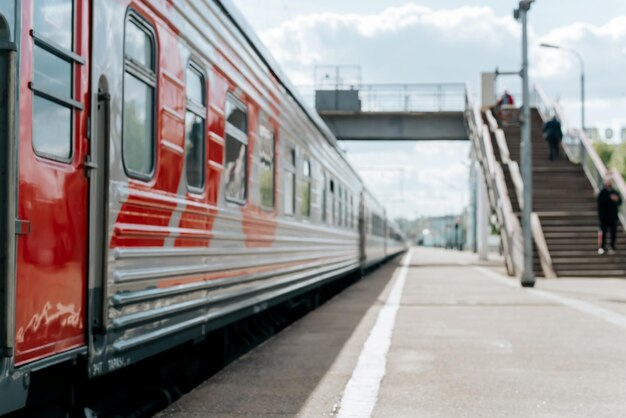 Treno passeggeri ad alta velocità moderno sfocato alla stazione ferroviaria e persone sulla piattaforma vista laterale all'aperto