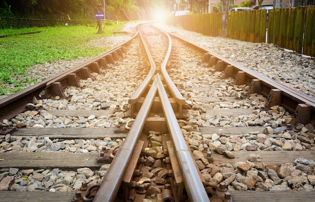 Treno piste su ghiaia, due dei binari ferroviari si fondono con lo sfondo del tramonto