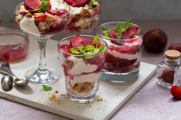 Trifles a strati con prugne rosse e panna montata in coppette da dessert