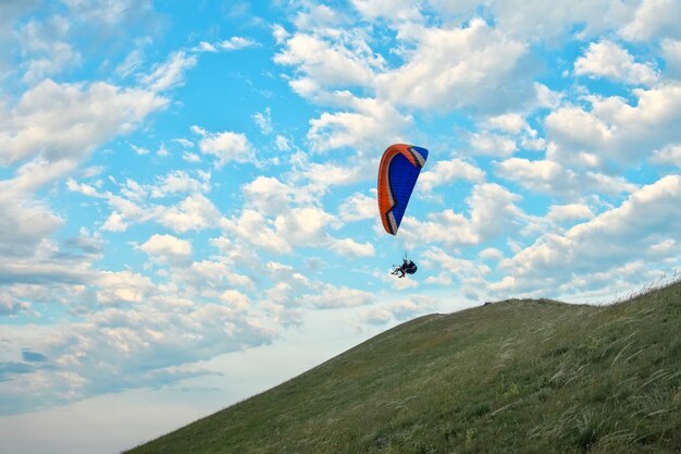 Trike con un paracadute contro il cielo blu. Parapendio in volo sopra le nuvole