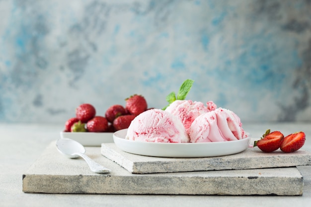 Trio di gustoso gelato alla vaniglia e fragola congelato dessert dessert in una ciotola con menta su una pietra