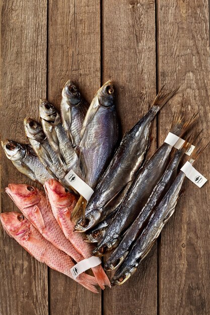 Triotto salato essiccato, pesce sciabola e triglie rosse con etichette sulle code su fondo di legno