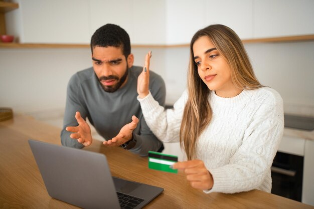 Triste coppia millenaria internazionale offesa che punta le mani al laptop usa lo shopping online con carta di credito