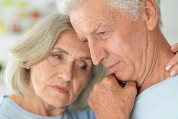 Triste coppia senior che abbraccia e posa a casa