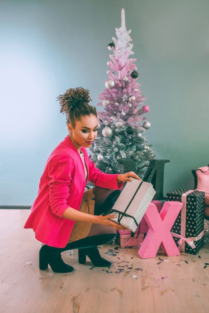 triste donna afroamericana vicino all'albero di Natale delusa dal regalo di natale