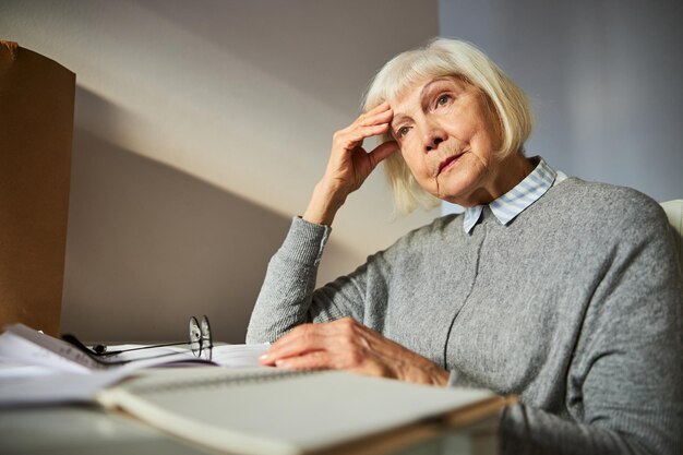 Triste donna invecchiata seduta alla scrivania