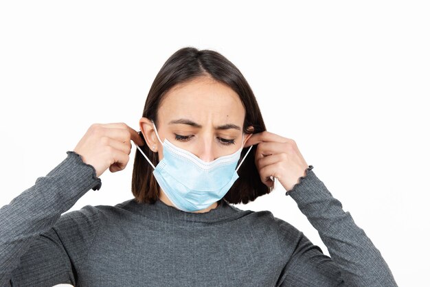 Triste donna latina che toglie la maschera medica. Assistenza sanitaria durante il concetto di pandemia di Coronavirus.
