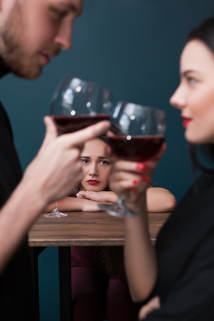 Triste donna rimasta sola al bar. Sfondo di gelosia. Rapporti traditori. Infelice donna sola a fuoco su sfondo blu, concetto di solitudine