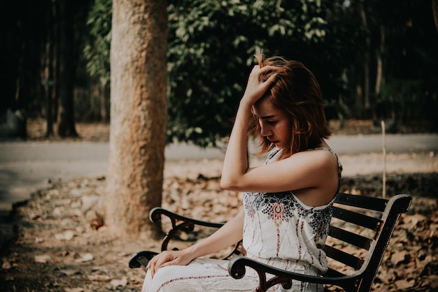 Triste donna seduta su una panchina nel parco in stile vintageHa superato la storia molto peggiore del concetto di crepacuore delle persone della Thailandia