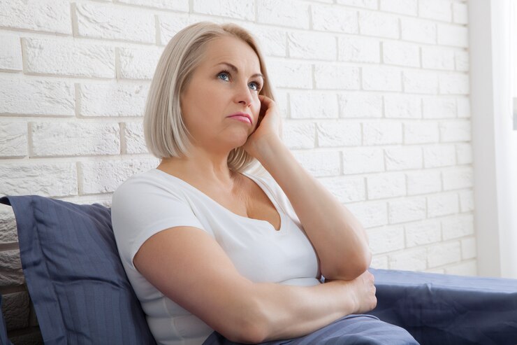 Foto triste donna seduta sul letto al mattino. menopausa depressa