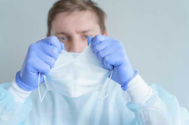 Triste dottore maschio stanco dal lavoro lacrime maschera per il viso Fine della quarantena pandemica Veste medicaguanti blu Disperazione dal trattamento di pazienti malati Combattere il coronavirus covid19 Infezione pericolosa Resta a casa