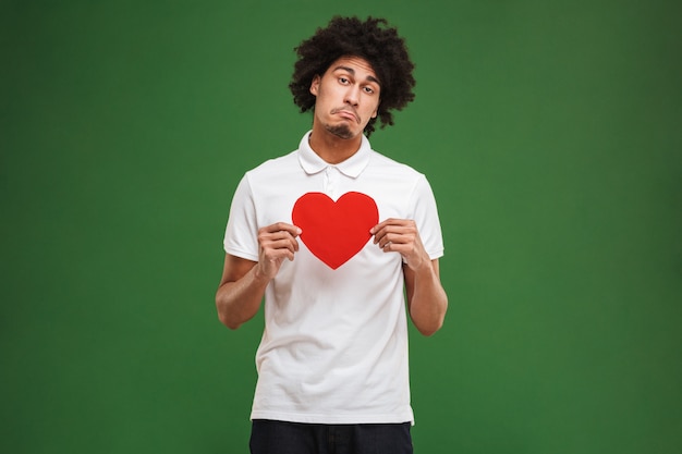 Triste giovane africano uomo riccio tenendo il cuore.