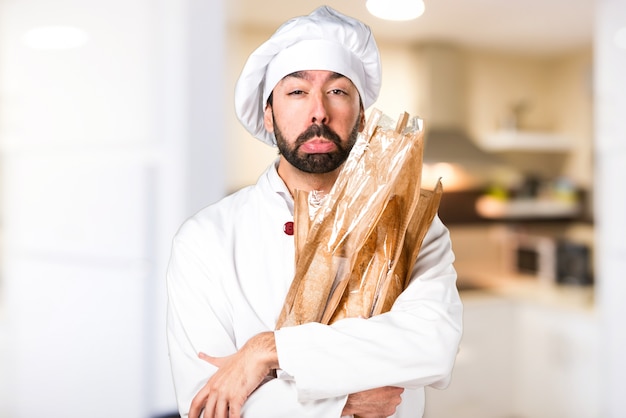 Triste giovane panettiere che tiene un po &#39;di pane in cucina