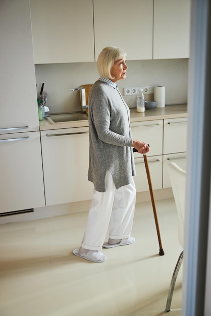 Triste pensionato solitario in piedi in cucina