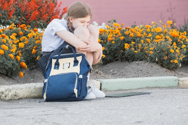 Triste ragazza disperata che soffre di bullismo e molestie che si abbattono solitaria, infelice disperata e senza speranza seduta all'aperto. Isolamento scolastico, abuso e concetto di bullismo