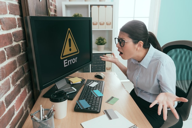 tristezza ufficio lavoratore signora che mostra confusa posa e guardando le informazioni di errore del computer perché tutte le sue carte di credito hanno rubato.