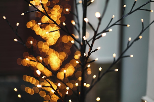 Tronco d'albero e rami in luci dorate bokeh in serata Mercato invernale delle vacanze