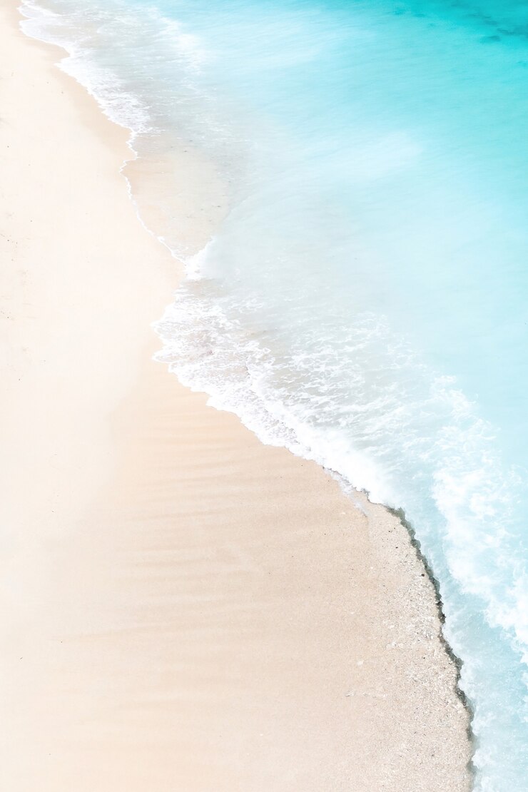 Tropical beach with a bird's eye view of the waves breaking on the tropical Golden sandy beach. Sea waves gently loop along the beautiful sandy beach.