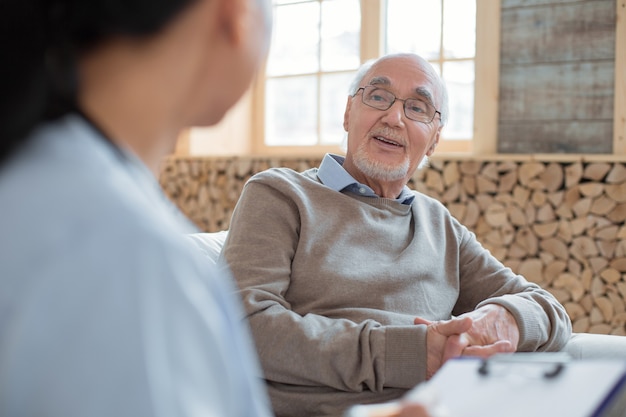 Troppo vecchio. Appunti della holding del medico mentre notando e ascoltando un uomo anziano allegro positivo