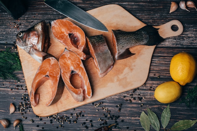 Trota affettata sulla tavola di legno con il limone e i condimenti