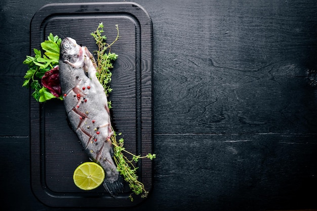 Trota di pesce con erbe aromatiche e spezie su fondo in legno