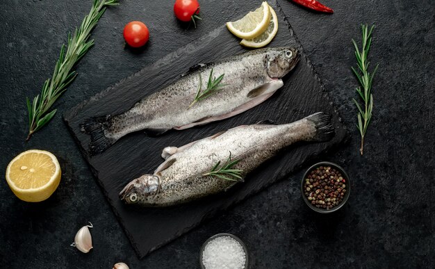 trota di pesce crudo con spezie pronte per la cottura su uno sfondo di pietra