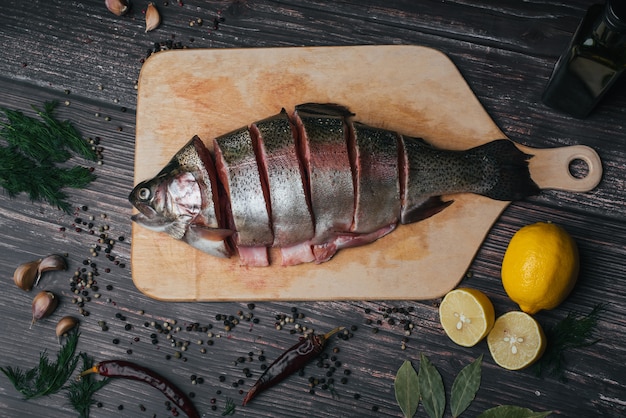 Trota fresca tagliata a pezzi su una tavola di legno. Pesce rosso crudo