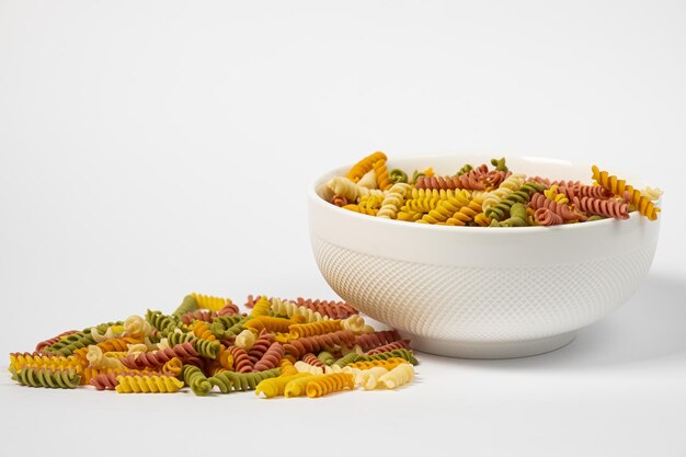 Trottole di pasta di grano tricolore in un piatto isolato su sfondo bianco