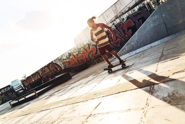 Trova la tua libertà! Per tutta la lunghezza del giovane che fa skateboard mentre esce allo skate park all'aperto