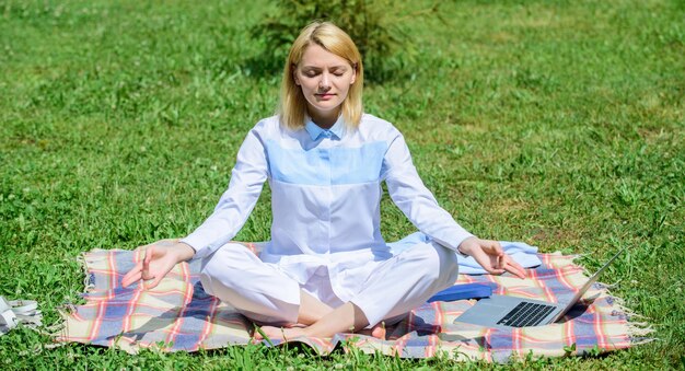 Trova un minuto per rilassarti. Meditazione praticante di rilassamento della donna. Meditazione quotidiana. Motivi per cui dovresti meditare ogni giorno. Schiarisciti le idee. La ragazza medita sul fondo della natura del prato dell'erba verde del tappeto.