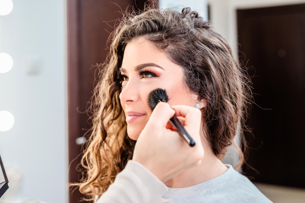 Truccatore che applica trucco professionale alla bella giovane donna.