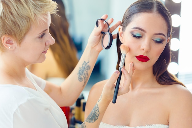 Truccatore che fa trucco professionale di giovane donna