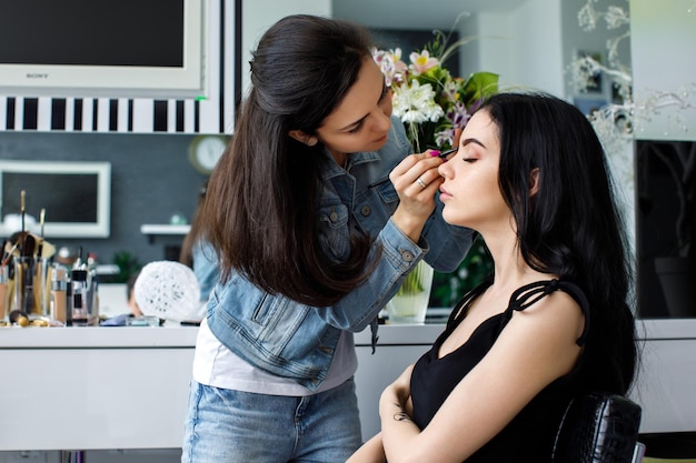 Truccatore che fa trucco professionale di una giovane modella