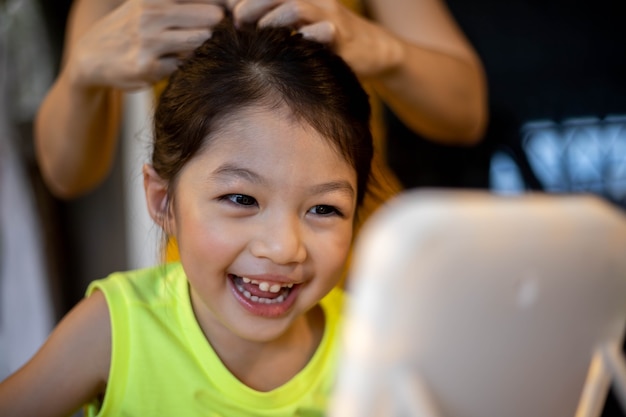 Trucco della madre per la figlia in camera. Concetto di famiglia felice.