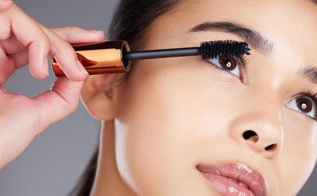 Trucco di bellezza viso e donna con mascara in studio isolato su sfondo grigio Estetica cosmetica e primo piano di giovane modello femminile con pennello o prodotto per la cura delle ciglia o del benessere