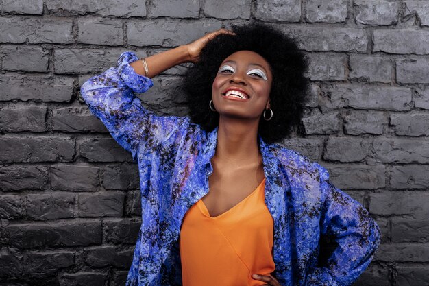 Trucco incredibile. Bella modella dai capelli scuri con grandi orecchini che sorridono brillantemente mentre posano