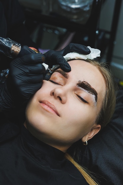 Trucco permanente Procedure di bellezza Il maestro applica un tatuaggio sulle sopracciglia Microblading facciale professionale Dispositivo per cosmetologia femminile