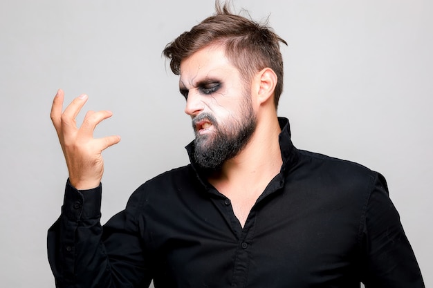 Trucco spaventoso in stile non morto per Halloween su un uomo barbuto che mostra gesti