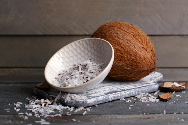 Trucioli di cocco in ciotola con cocco su sfondo di legno