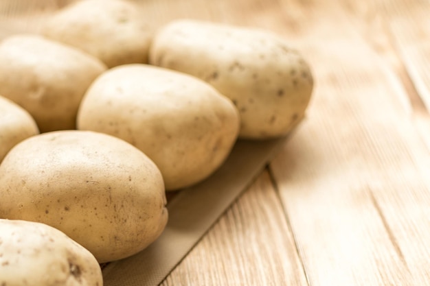 Tuberi di patata crudi su un fondo di legno