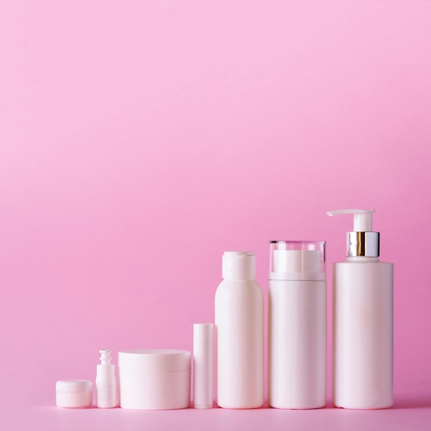 Tubi cosmetici bianchi su sfondo rosa con spazio per la copia Concetto di bellezza per il trattamento del corpo per la cura della pelle Raccolto quadrato